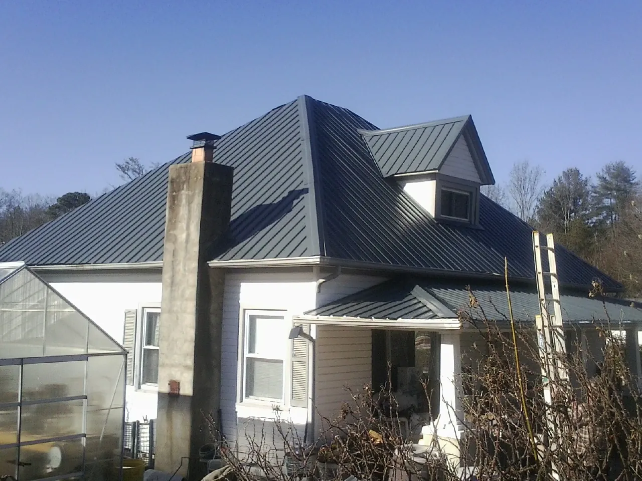 Dark blue standing seam metal roof on a white farmhouse with dormer — Slate & Tile Roof Repair by Roofing Brothers in Onancock