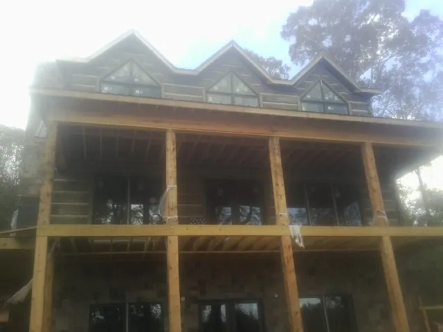 Dormers and porch framing on a large log home under construction — Roof Coating work by our crew in Onancock