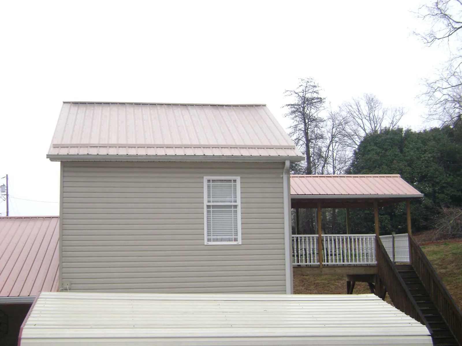 Tan metal roofs on a two story addition and attached porch, from a Roof Replacement job in Onancock