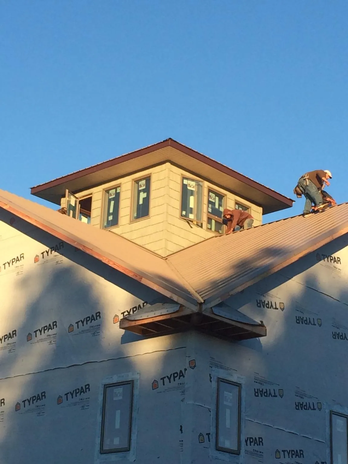 Roofers working around a rooftop cupola on a new metal roof at sunset — Roof Waterproofing in Onancock by Roofing Brothers